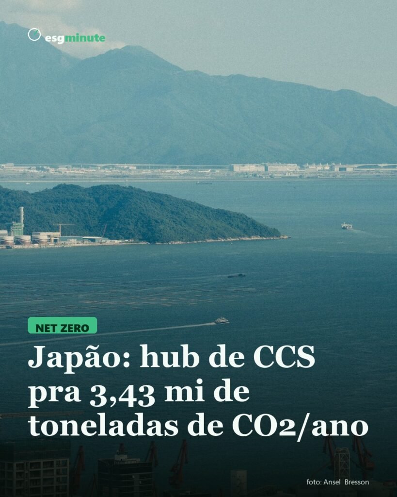 Baía com área industrial à beira-mar e montanhas ao fundo