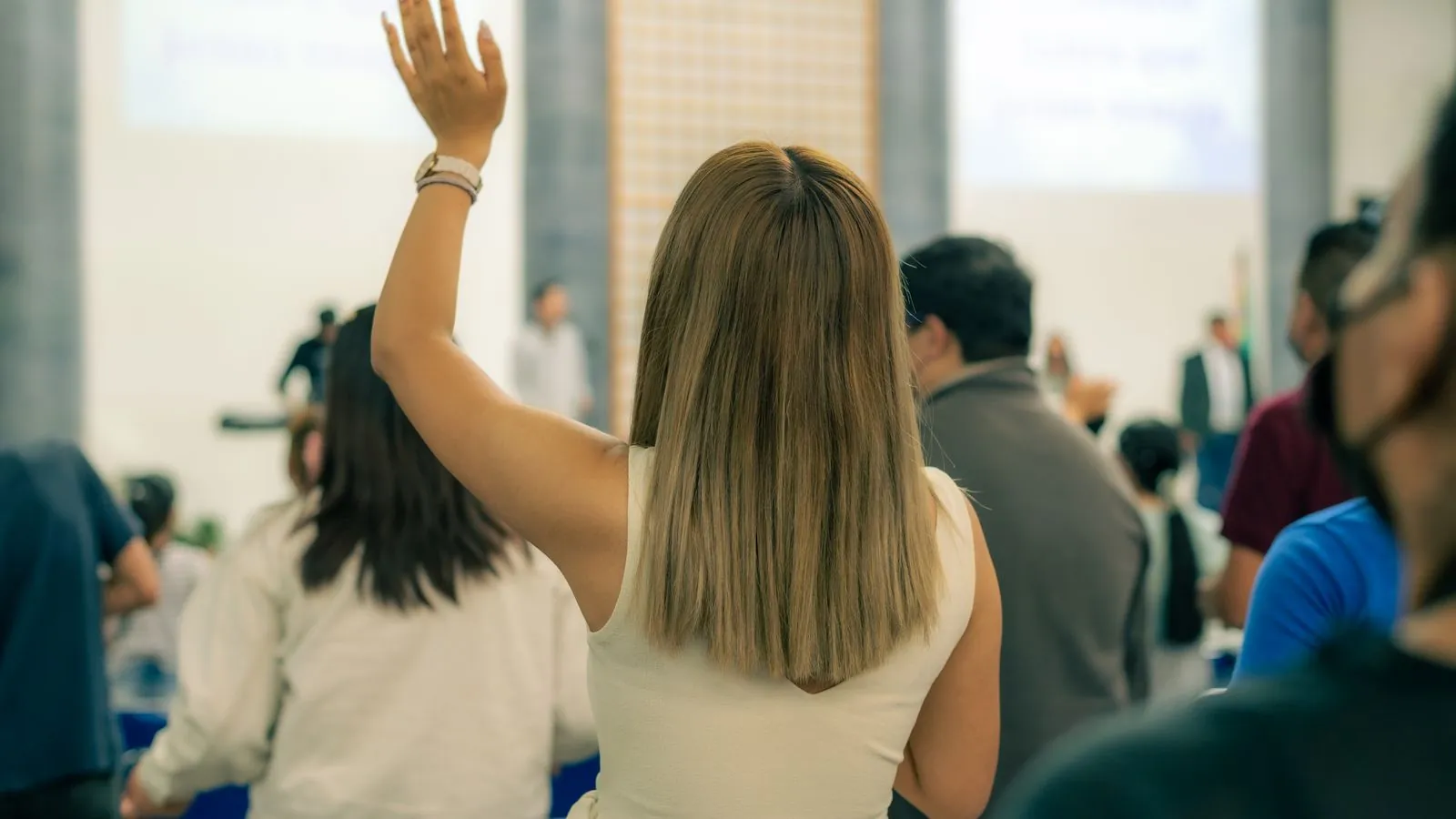 Pessoas levantando a mão numa reunião